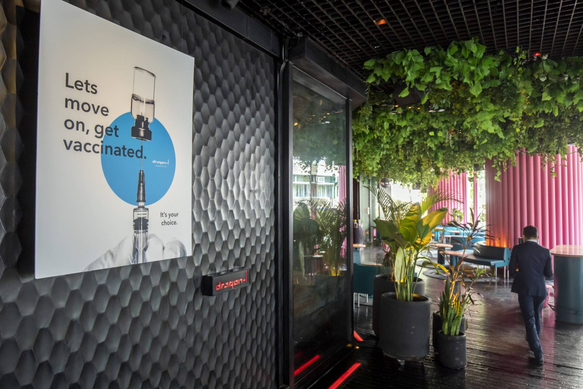 A poster at a nightclub in the Lan Kwai Fong nightlife area of Hong Kong encourages people to get vaccinated . | Bloomberg 