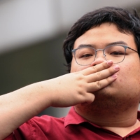 Thai protest leader Parit \"Penguin\" Chiwarak flashes a three-finger salute as he arrives at the criminal court in Bangkok in February.  | REUTERS 