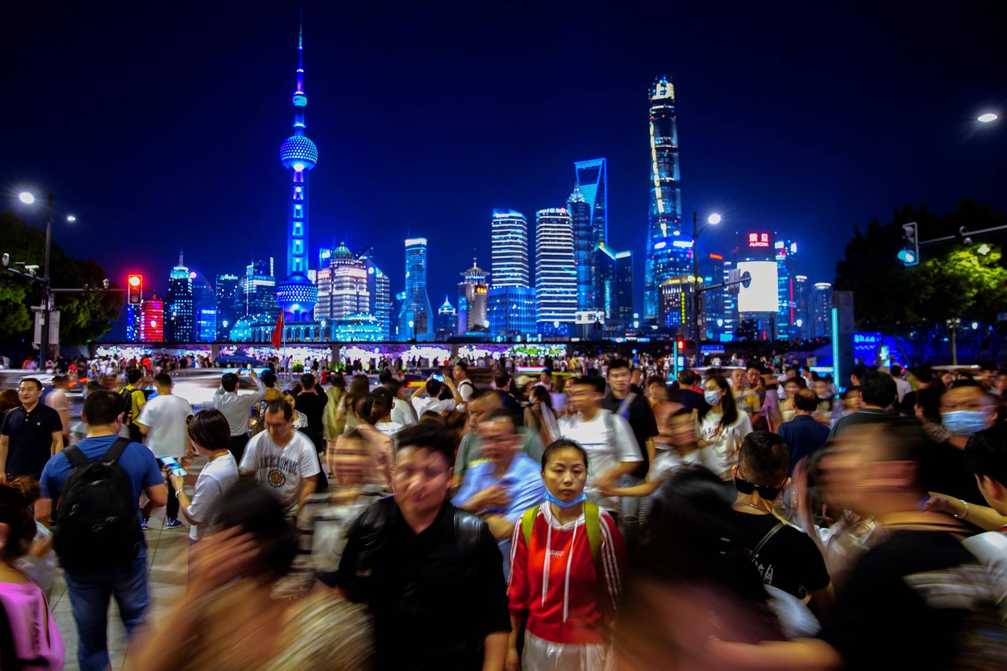 People walk near the Bund, as Shanghai's Lujiazui financial district is seen in the background, on Monday. China on Tuesday announced its slowest population growth since the 1950s, sharply reducing the size of the labor force as the nation ages, and worsening demographic pressures in the economy. | REUTERS