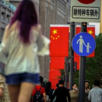 People walk along the Nanjing Pedestrian Road shopping area in Shanghai on Monday. China on Tuesday announced its slowest population growth since the 1950s, sharply reducing the size of the labor force as the nation ages, and worsening demographic pressures in the economy. | REUTERS