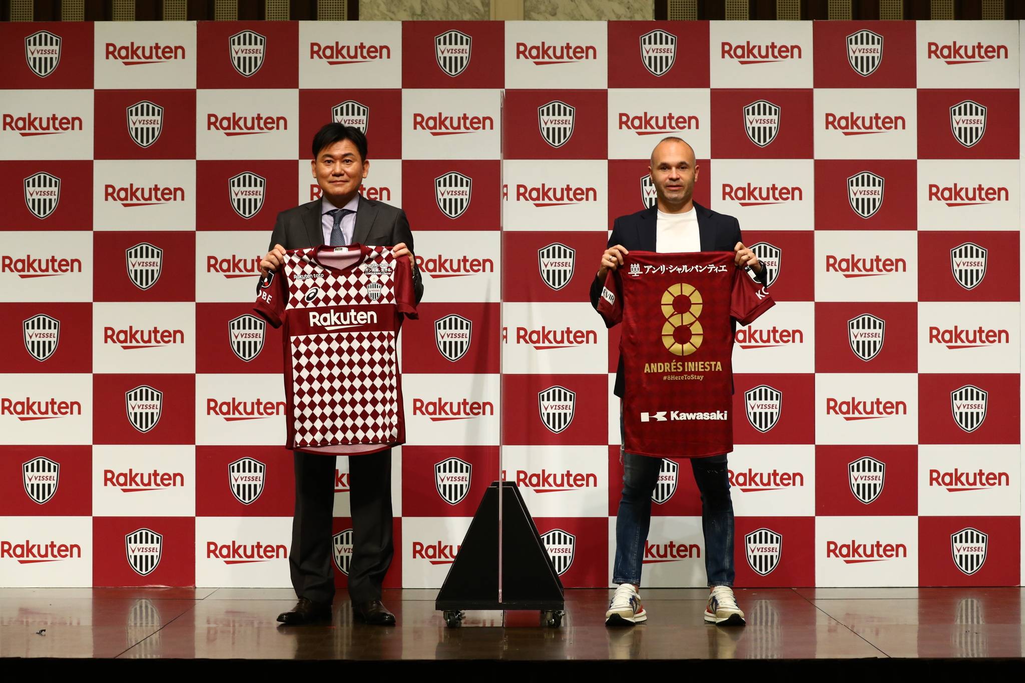 Vissel owner Hiroshi Mikitani and midfielder Andres Iniesta pose with uniforms commemorating the latter's contract extension. | VISSEL KOBE