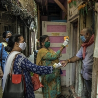Health workers doing contact tracing check the body temperature and blood oxygen level of a man in Mumbai in April.  | ATUL LOKE/  THE NEW YORK TIMES