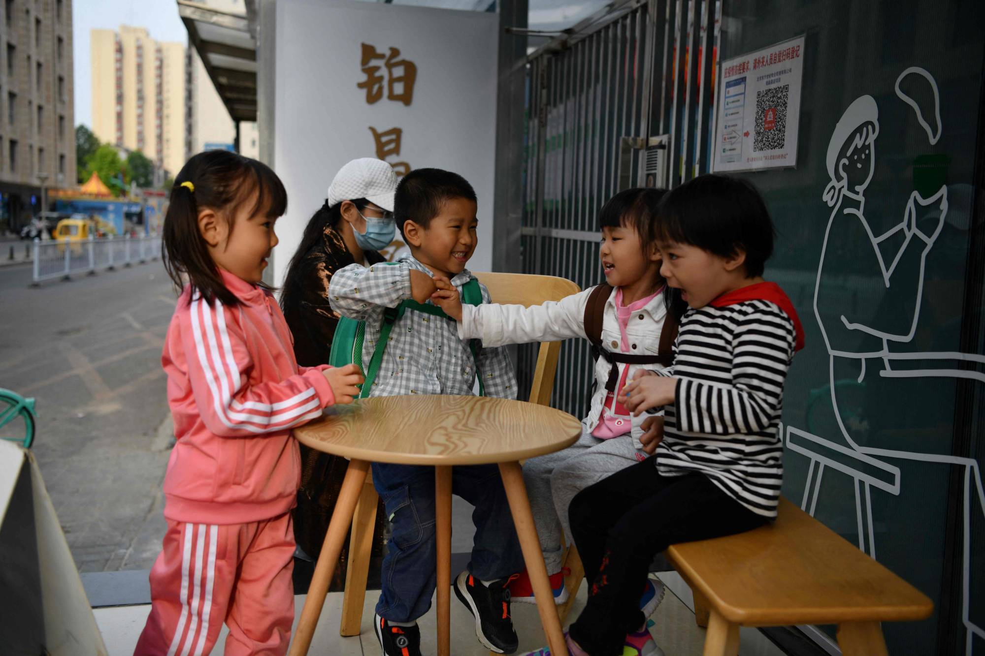 Children play outside a cafe in Beijing on Tuesday. Because it’s betting on productivity gains, demographers don’t expect China’s government to launch an all-out effort to raise births. | AFP-JIJI
