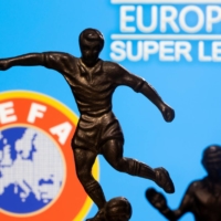 Metal figures of soccer players are seen in front of the words \"European Super League\" and the UEFA logo in an illustration taken April 20. | REUTERS