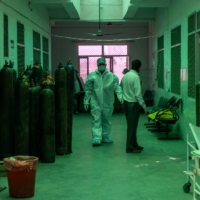 A health-care worker walks past oxygen cylinders outside a COVID-19 intensive care unit at a hospital in Bijnor district, Uttar Pradesh, India, on Tuesday. | REUTERS