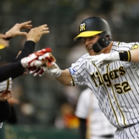 The Tigers\' Jerry Sands celebrates with his teammates after giving Hanshin the lead with a solo home run in the eighth inning on Thursday at Koshien Stadium. | KYODO