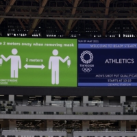 An image reminding fans to maintain social distance is displayed on a video board at National Stadium during a test event on Sunday. | KIYOSHI OTA / BLOOMBERG
