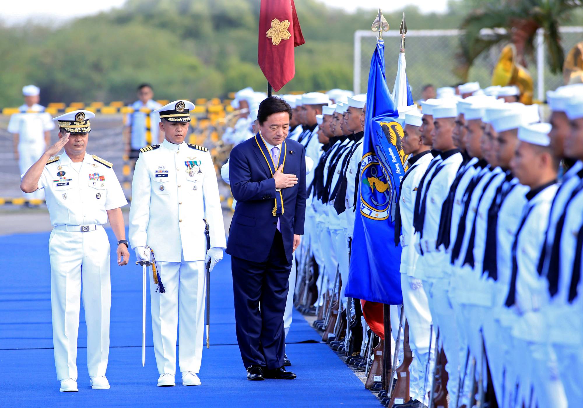 Japan's then-state minister of defense, Kenji Wakamiya (center), reviews an honor guard during a transfer ceremony of Japanese training aircraft to the Philippine Navy at a naval facility south of Manila in March 2017.  | REUTERS 