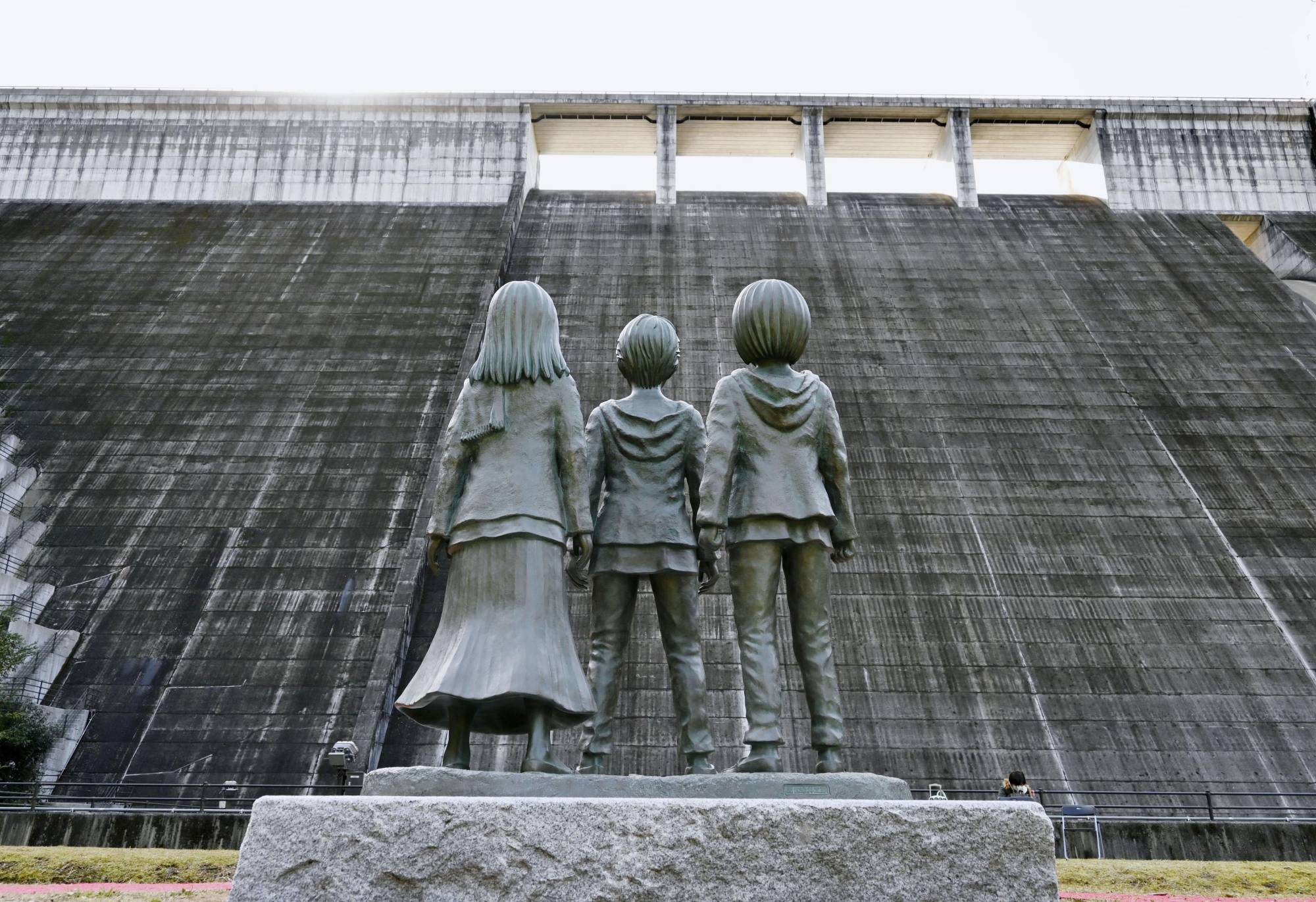 Us against the world: A bronze statue of 'Attack on Titan' protagonist Eren Yeager (center) and other characters in the manga series stands downstream of Oyama Dam in Oita Prefecture. The monument is a reproduction of a famous scene in which the trio encounter the Titans.  | KYODO