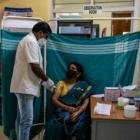 A woman receives a dose of Covishield, a COVID-19 vaccine manufactured by Serum Institute of India, at a vaccination center in Bangalore on Thursday. | REUTERS