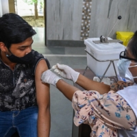 A health worker inoculates a man with a dose of the Covishield COVID-19 vaccine at a vaccination center in New Delhi on Thursday. | AFP-JIJI