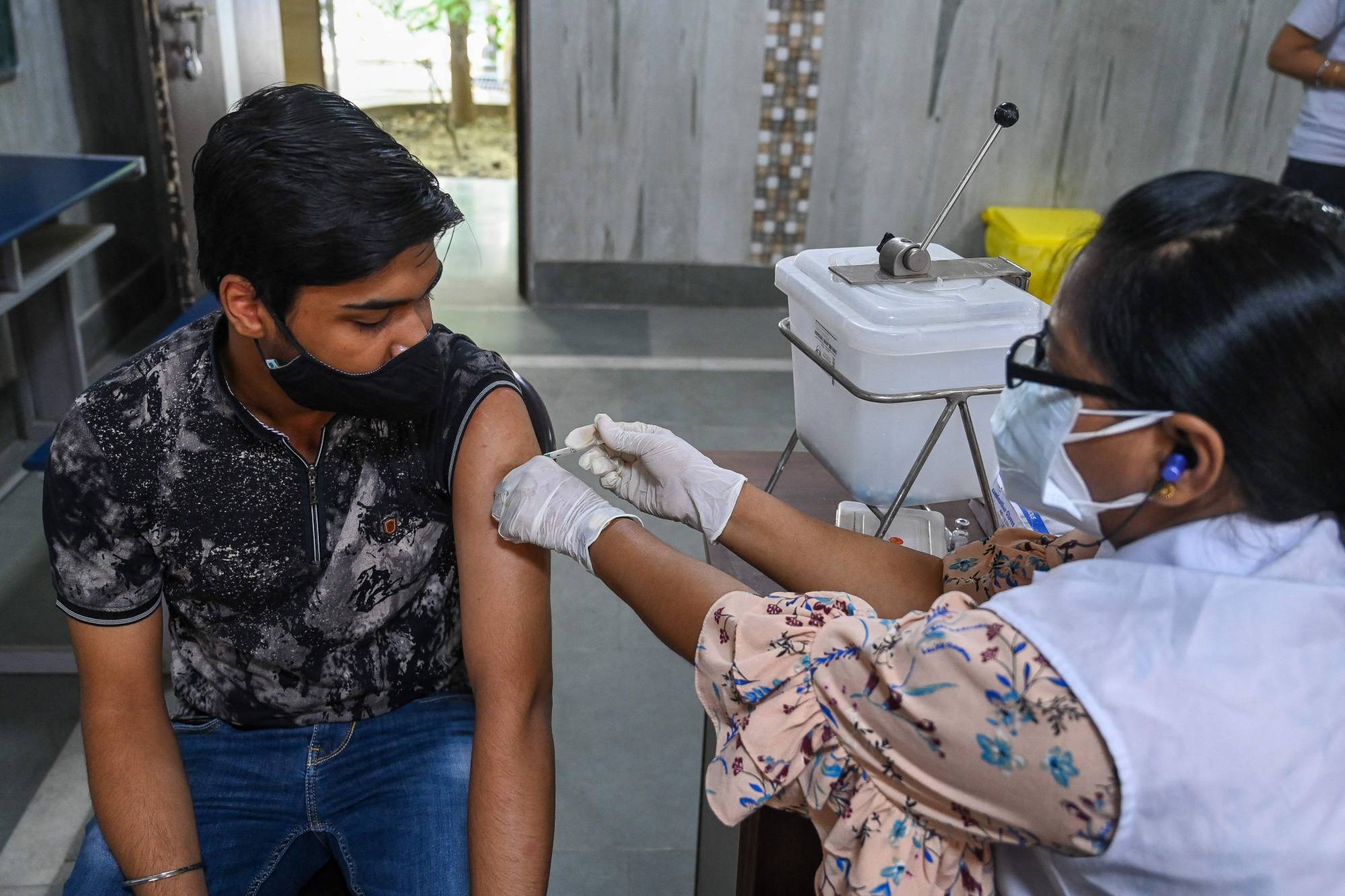 A health worker inoculates a man with a dose of the Covishield COVID-19 vaccine at a vaccination center in New Delhi on Thursday. | AFP-JIJI