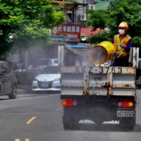 A worker sprays disinfectant around a temple in New Taipei City on Thursday as coronavirus cases surge in Taiwan.  | AFP-JIJI