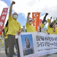 Protesters demonstrate in front of the entrance to U.S. Marine Corps Camp Foster in Kitanakagusuku, Okinawa Prefecture, on Saturday, the 49th anniversary of Okinawa\'s reversion to Japan from U.S. control. | KYODO