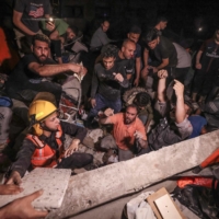 Palestinian firefighters search urgently for survivors and bodies under the rubble after an intensive civilian bombardment of Gaza City on Sunday.  | AFP-JIJI