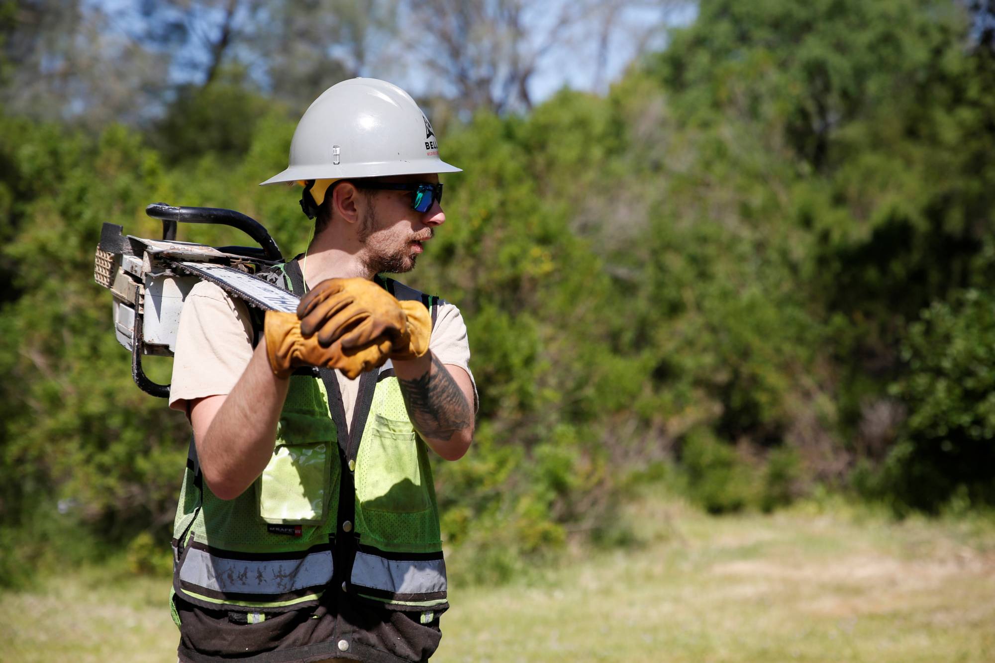 Private firefighter Sean Pafford carries his chainsaw after cutting dead tree limbs as part of a fire prevention project at a park outside Sacramento, California, on April 5. | Reuters