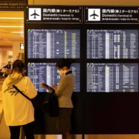A staff member helps a passenger at Haneda Airport in Tokyo on April 30. | AFP-JIJI