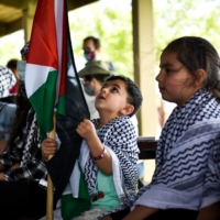 Children sit among people supporting Palestinians during a rally in Dearborn, Michigan, on Tuesday as U.S. President Joe Biden visited a nearby car plant.  | EMILY ROSE BENNETT / THE NEW YORK TIMES