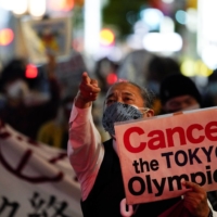Against the games: An anti-Olympics group member holds a “Cancel the Tokyo Olympics” sign during a protest march in Tokyo on May 17. A spike in coronavirus cases may have people saying to themselves, \"Kotoshi, Orinpikku o kaisai dekiru wake ga nai.\" | REUTERS