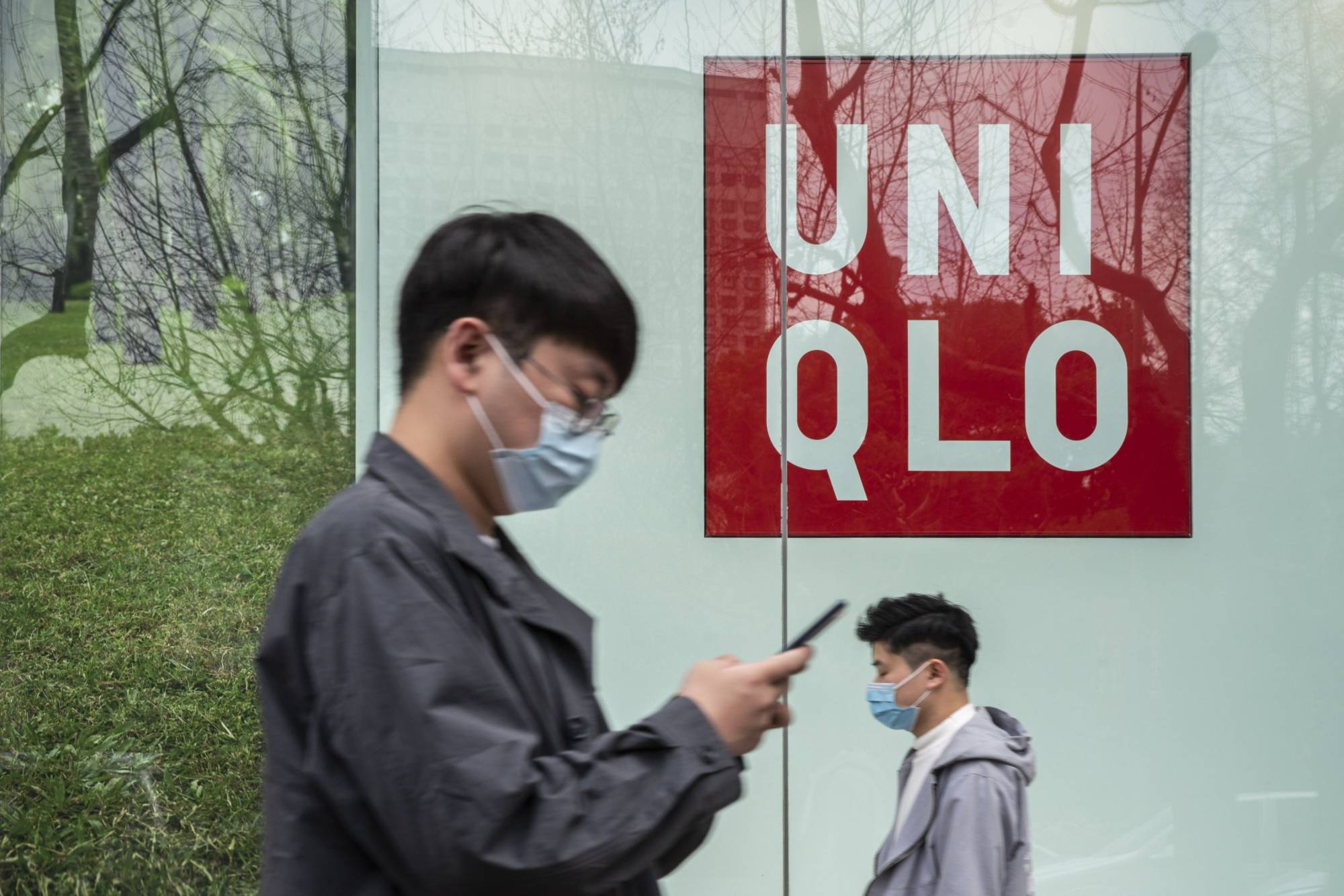 Pedestrians walk past a Uniqlo store, operated by Fast Retailing Co., in Shanghai in March. The U.S. customs agency blocked a shipment of Uniqlo shirts in January as the company failed to provide enough information to establish the items were not produced in part by forced labor in China’s Xinjiang region. | BLOOMBERG