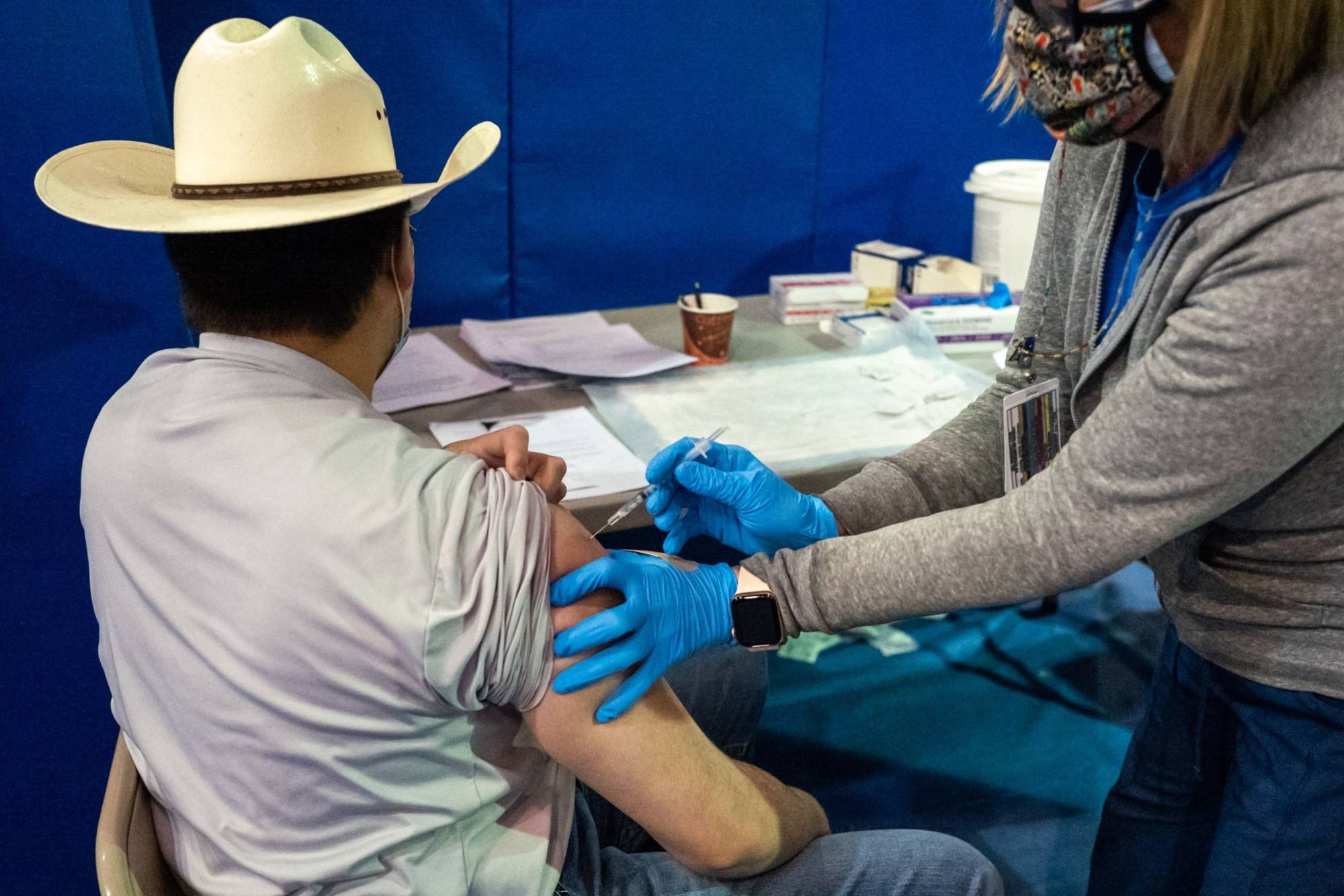 A health care worker administers a dose of the Pfizer COVID-19 vaccine at the University of New Mexico's Gallup campus on March 23. | BLOOMBERG 