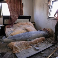 A person looks out a bedroom window where an unexploded Israeli missile landed on a bed in Khan Yunis, Gaza Strip, on Thursday. | SAMAR ABU ELOUF / THE NEW YORK TIMES