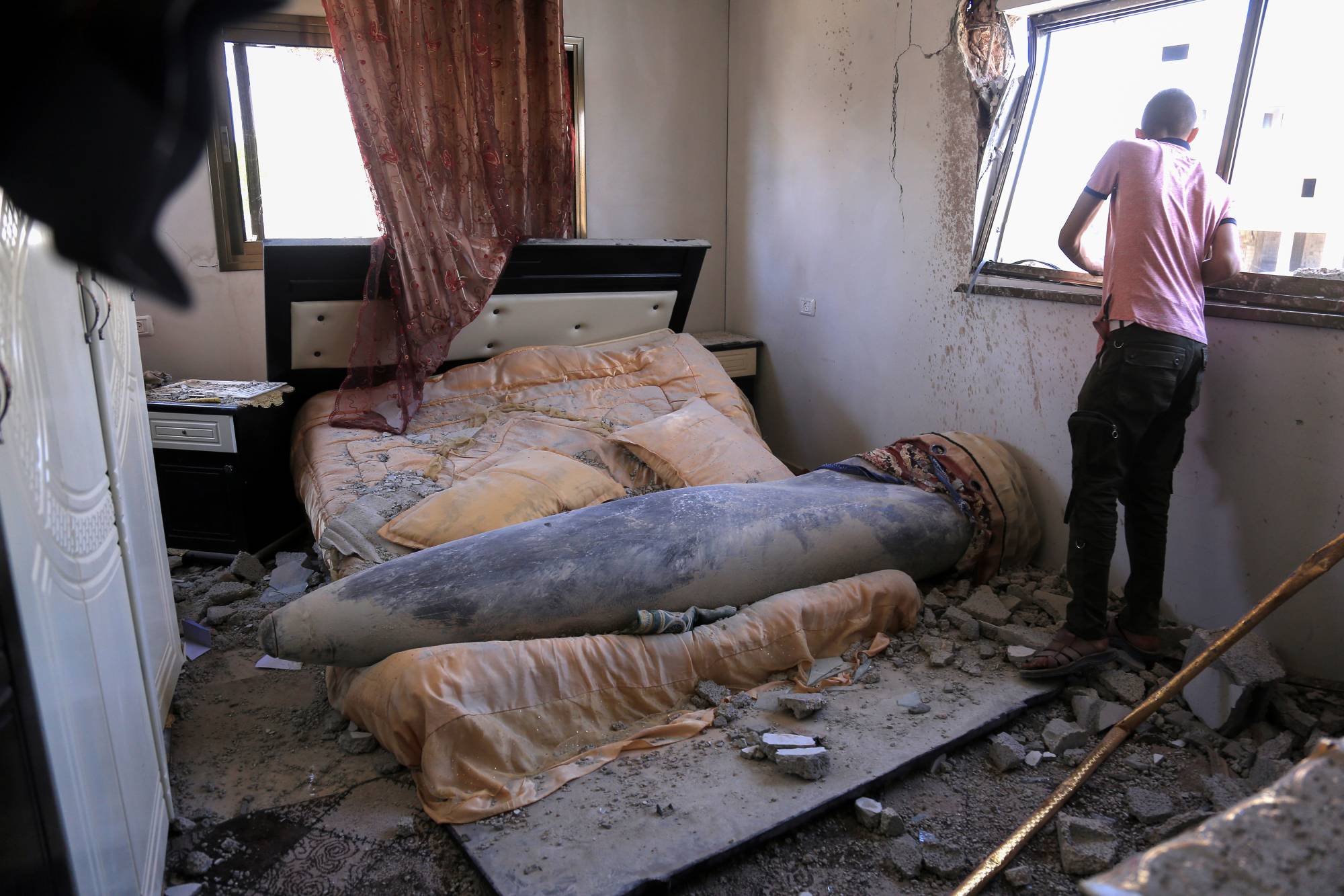 A person looks out a bedroom window where an unexploded Israeli missile landed on a bed in Khan Yunis, Gaza Strip, on Thursday. | SAMAR ABU ELOUF / THE NEW YORK TIMES