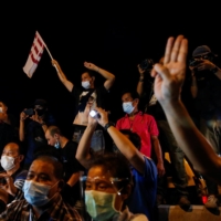 Supporters of anti-government protest leaders arrested and charged with lese majeste show the three-finger salute next to members of the media as they are released in Bangkok on May 11. | REUTERS