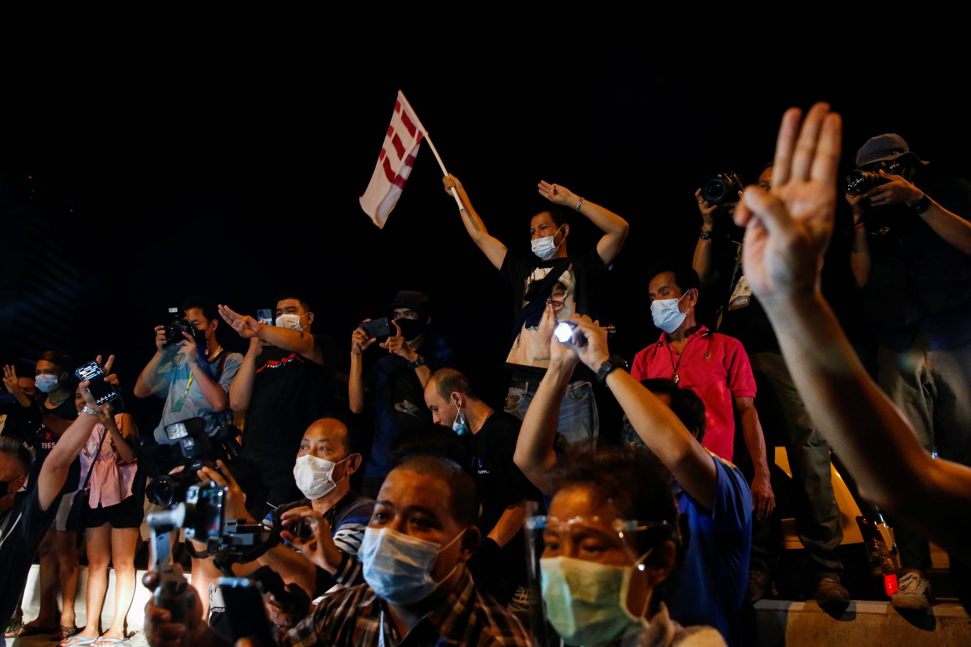 Supporters of anti-government protest leaders arrested and charged with lese majeste show the three-finger salute next to members of the media as they are released in Bangkok on May 11. | REUTERS