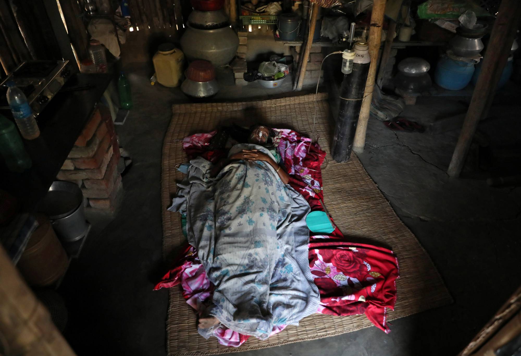 A woman with COVID-19 receives oxygen support inside her house in the village of Debipur in India's West Bengal state. | Reuters