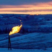 A natural gas flare on an oil well pad burns as the sun sets outside Watford City, North Dakota. | REUTERS