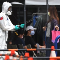 A soldier disinfects a person departing a COVID-19 testing site in Taipei on Wednesday.  | REUTERS 