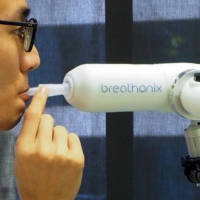 A staff member demonstrates the Breathonix breathalyzer test kit, which is able to detect COVID-19 within a minute, at a laboratory in Singapore in October 2020. | REUTERS 