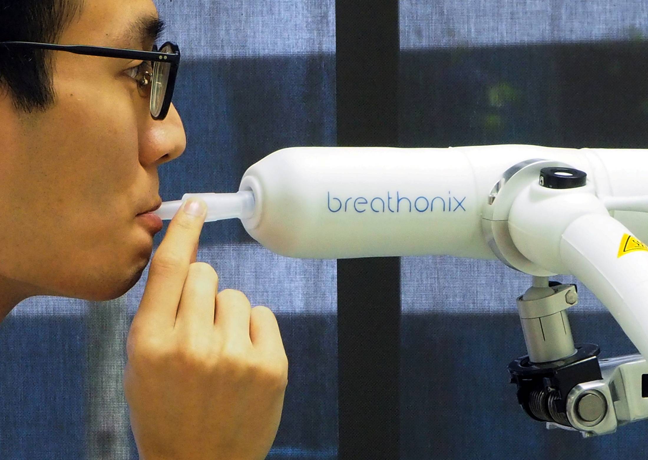 A staff member demonstrates the Breathonix breathalyzer test kit, which is able to detect COVID-19 within a minute, at a laboratory in Singapore in October 2020. | REUTERS 