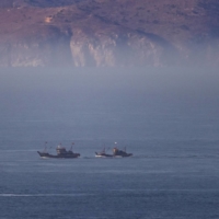 Fishing boats sail through the waters between the North Korean territory of Changsan Cape (rear) and Baengnyeong Island, South Korea, on March 29.  | BLOOMBERG