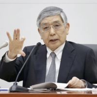 Bank of Japan Gov. Haruhiko Kuroda says he is starting to see the light at the end of the dark pandemic tunnel thanks to the rollout of COVID-19 vaccines. | POOL / VIA KYODO