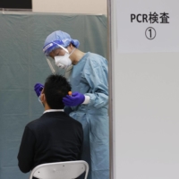 A quarantine official conducts a COVID-19 test on a passenger after their arrival at Narita Airport. | KYODO