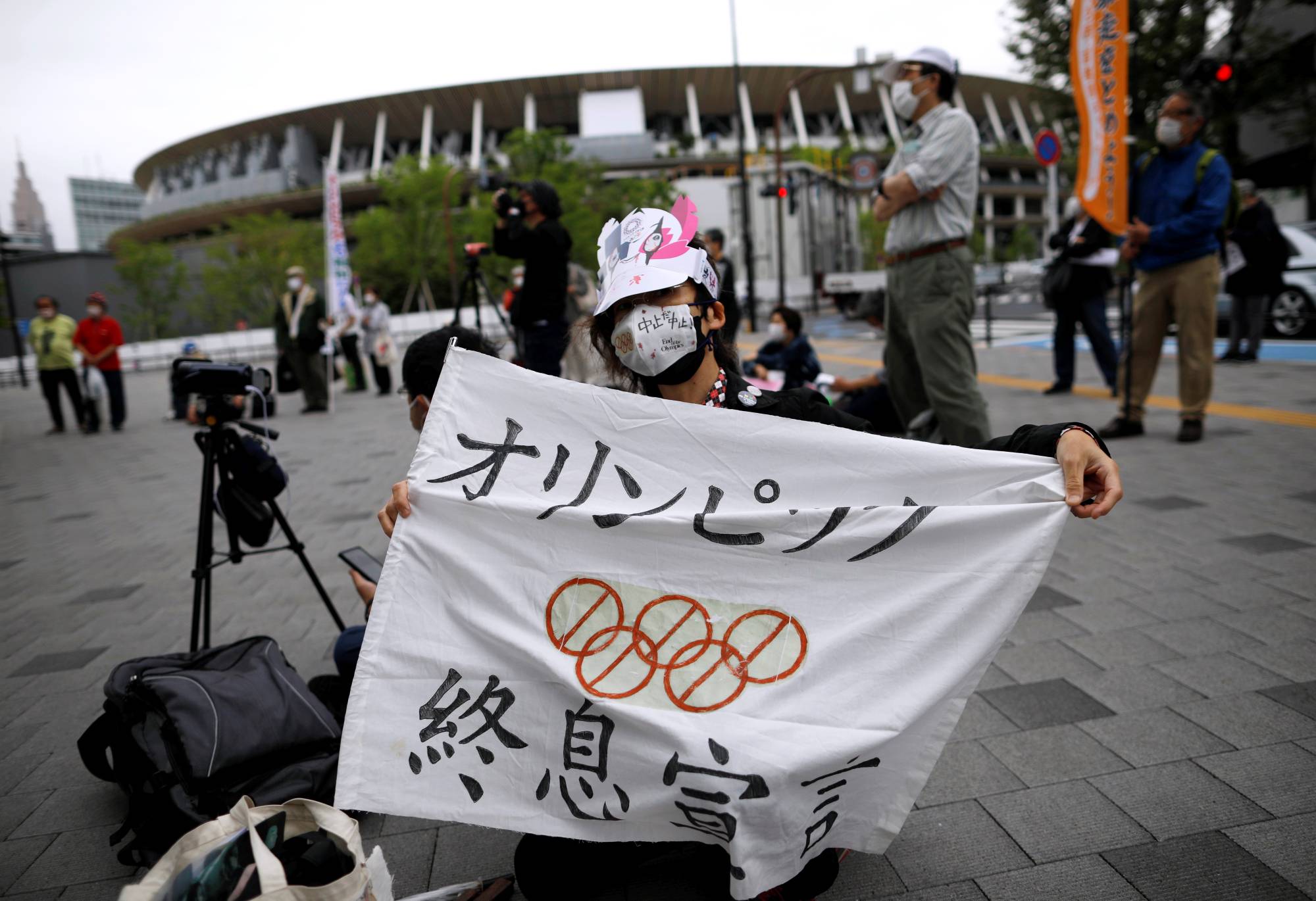 Anti-Olympics protester shows off a banner with the National Stadium in the background outside the Japanese Olympic Committee's headquarters during a rally in Tokyo last week. | Reuters