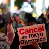 A member of an anti-Olympic group holds a sign during a protest march in Tokyo this month, as the capital grapples with a fourth wave of coronavirus infections. | REUTERS