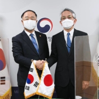 South Korean Finance Minister Hong Nam-ki (left) poses for a photo with Japanese Ambassador to Seoul, Koichi Aiboshi, prior to their meeting at the government complex in Seoul on April 7. | SOUTH KOREAN MINISTRY OF ECONOMY AND FINANCE / VIA KYODO
