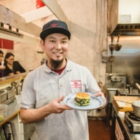 Keizo Shimamoto holding a ramen burger, which he debuted in Brooklyn in 2013 to massive fanfare. | COURTESY OF KEIZO SHIMAMOTO

