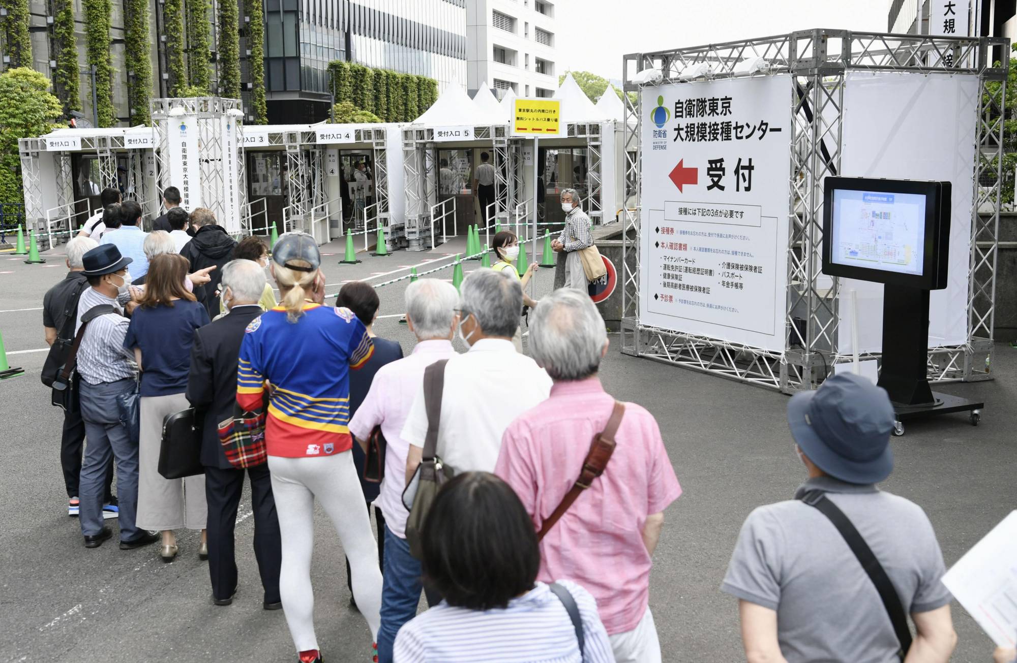 People line up in front of a mass-inoculation center in Tokyo's Chiyoda Ward on Wednesday to be vaccinated against COVID-19. | KYODO