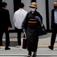 A woman walks through a shopping district in Tokyo on Friday. | REUTERS