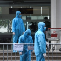 Medical workers stand outside a quarantined building in Hanoi earlier this year.  | REUTERS 