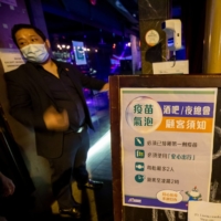 A notice about vaccine requirements at the entrance to a bar and restaurant in Hong Kong\'s Lan Kwai Fong nightlife area on April 29 | BLOOMBERG 