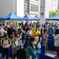 People line up outside a community vaccination center in Hong Kong on April 26. | BLOOMBERG 