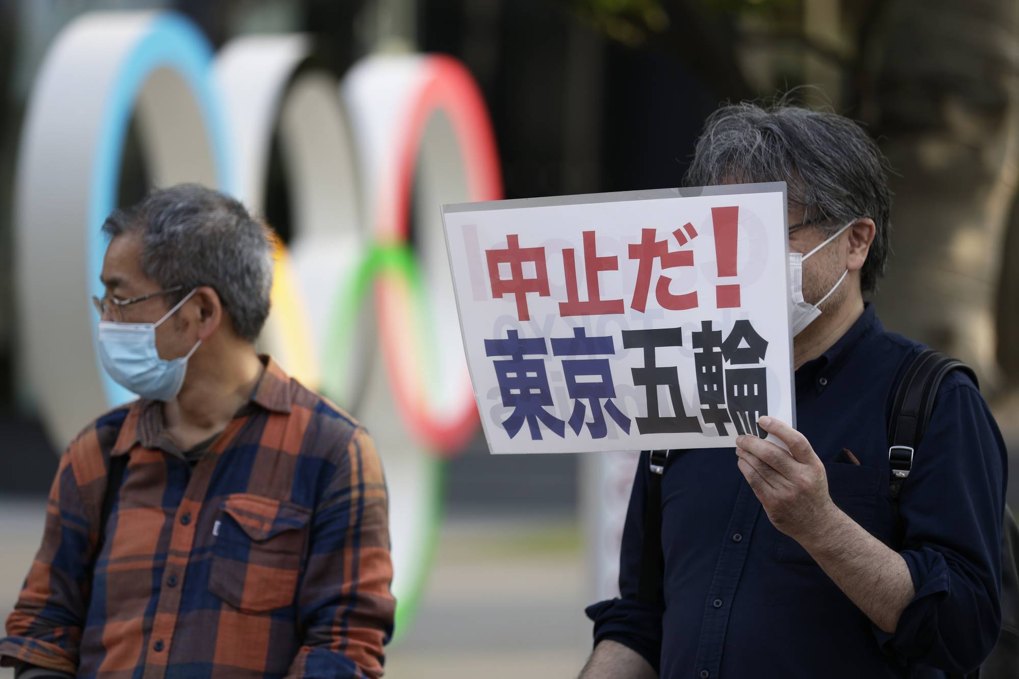 A protester holds a sign calling for the cancellation of the Summer Olympics, near the National Stadium in Tokyo on May 9. | BLOOMBERG