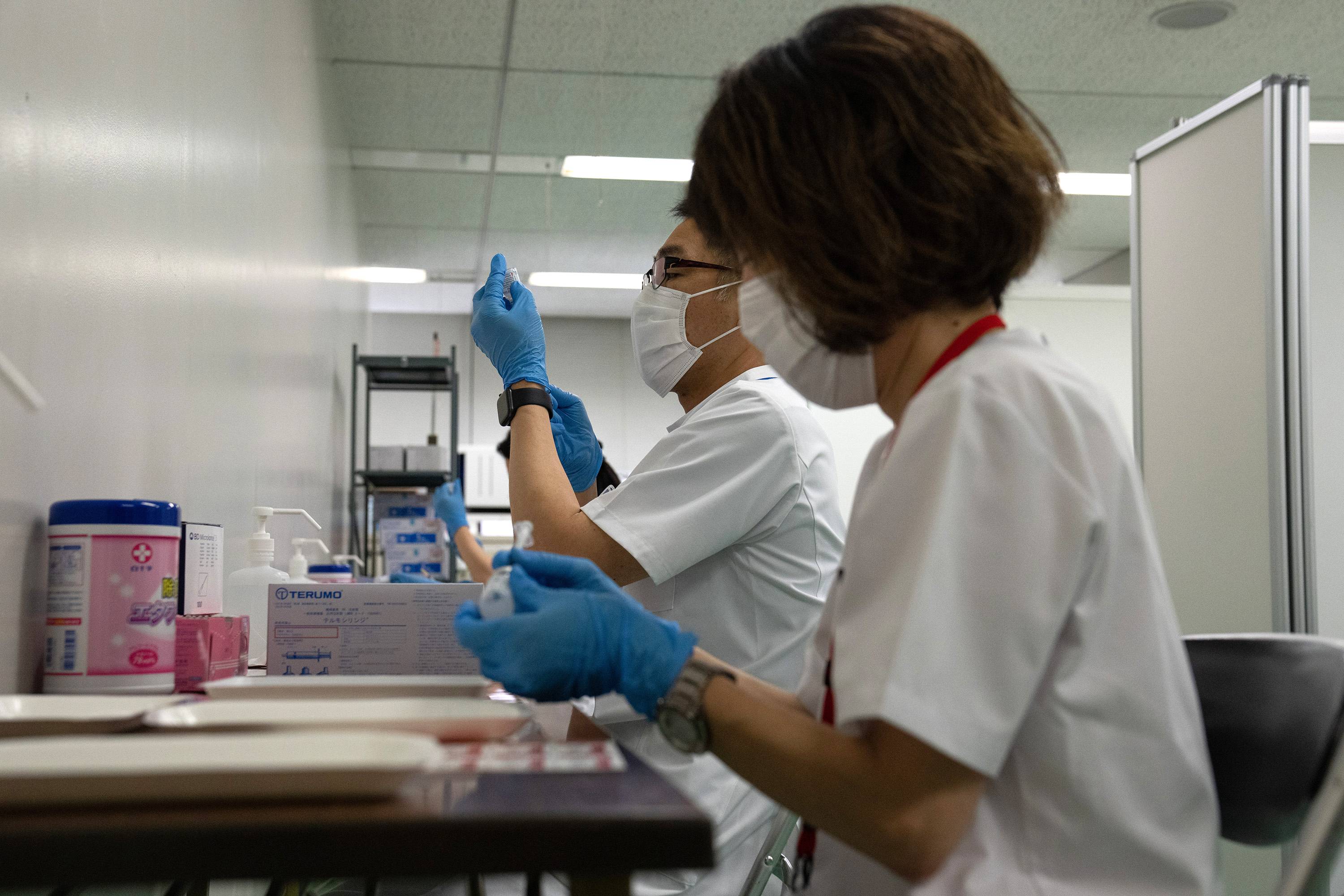 Medical workers fill syringes with doses of a COVID-19 vaccine at a newly opened mass vaccination site in Tokyo on May 24. | BLOOMBERG