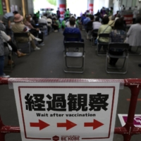 People wait in an observation area after receiving a dose of the Pfizer-BioNTech COVID-19 vaccine at a mass-inoculation site at Noevir Stadium Kobe on Tuesday. After some false starts, Japan\'s much-delayed vaccine rollout is quietly picking up steam, now administering between 400,000 and 500,000 doses a day.  | BLOOMBERG