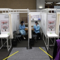 A man leaves after receiving a dose of the Pfizer-BioNTech COVID-19 vaccine at a mass-inoculation site at Noevir Stadium Kobe on Tuesday. After some false starts, Japan\'s much-delayed vaccine rollout is quietly picking up steam, now administering between 400,000 and 500,000 doses a day.  | BLOOMBERG